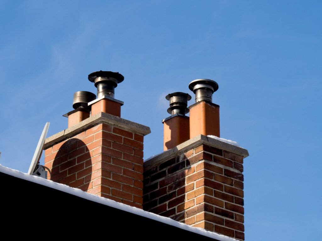 Row of brick chimneys on a rooftop against the sky